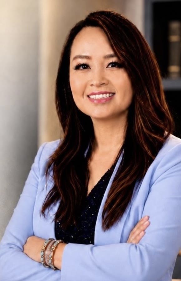 Kimly Hoang-Nakata, M.Ed., in a periwinkle blazer, arms crossed, smiling